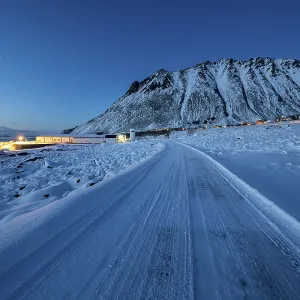Iced snow road, illuminated village in twilight Iced snow road, illuminated village in twilight