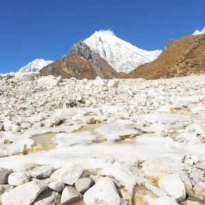Icy alpine river running through white rocky terrain landscape at high elevation alpine tundra with Langtang Lirung Icy alpine river running through white rocky terrain landscape at high elevation alpine tundra with Langtang Lirung