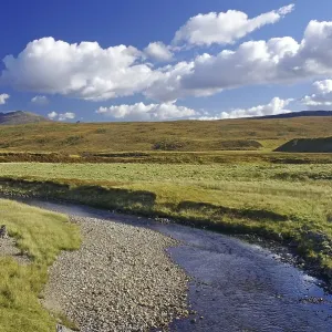 Idyllic river landscape with mountains in the background under a blue sky Idyllic river landscape with mountains in the background under a blue sky