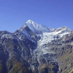 Impressive mountain peak with glacier under bright blue sky