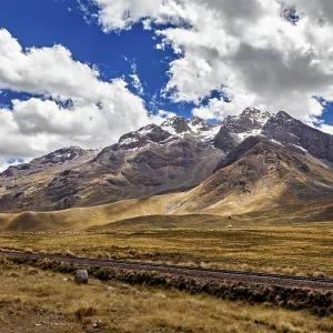 Impressive mountain range with snowy peaks under a cloudy blue sky