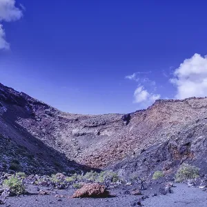 Impressive volcano crater with low vegetation under a blue sky