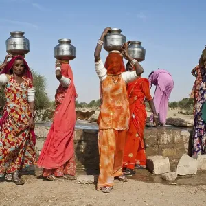 Indian women wearing saris carrying water jugs on their heads Indian women wearing saris carrying water jugs on their heads