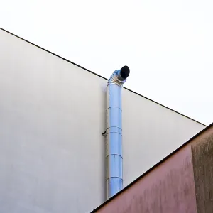 Industrial pipe extending along a minimalistic white wall with geometric shapes