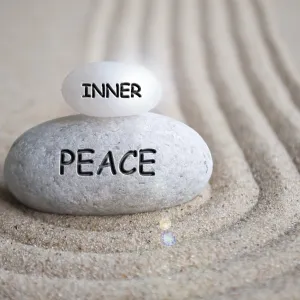 Inner peace text engraved on Zen stone on sand with shining