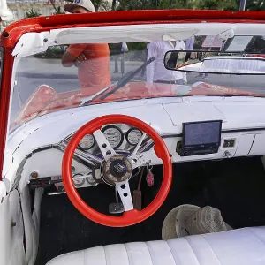 The interior of a classic car with detailed dashboard and red steering wheel The interior of a classic car with detailed dashboard and red steering wheel