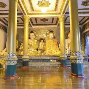 Interior of the temple with golden Buddha statues on a decorated pedestal