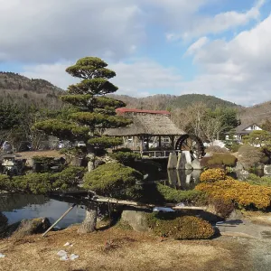 Japanese garden with traditional house and well-kept trees against mountain backdrop Japanese garden with traditional house and well-kept trees against mountain backdrop