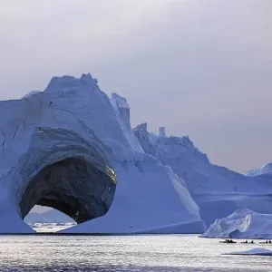 Kayaks in front of huge iceberg with cave Kayaks in front of huge iceberg with cave
