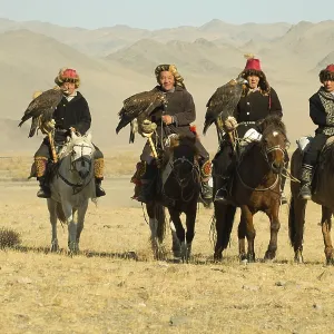 Four Kazakh eagle hunters on their horses on the way to the Eagle Festival in Sagsai