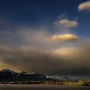 Lake Hopfensee with stormy sky in soft morning light and Allgaeu mountains in the background Lake Hopfensee with stormy sky in soft morning light and Allgaeu mountains in the background