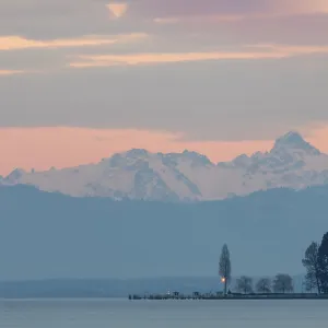 Lake in front of snowy mountains at sunset with pink sky Lake in front of snowy mountains at sunset with pink sky