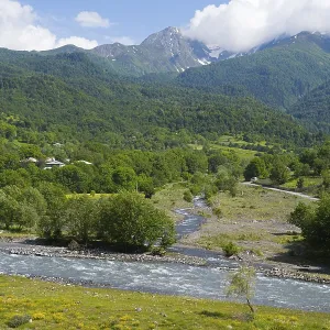 Landscape with a river snaking through green mountains and forests with meadows