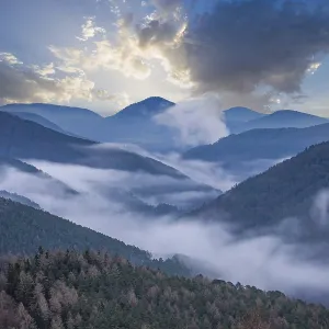Landscape shot with cloudy sky and fog in the valley Landscape shot with cloudy sky and fog in the valley