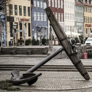 A large anchor sculpture on a cobblestone path surrounded by colorful buildings in Nyhavn A large anchor sculpture on a cobblestone path surrounded by colorful buildings in Nyhavn