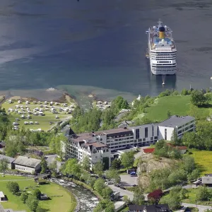 A large cruise ship is moored on a shore with many buildings and green meadows and trees A large cruise ship is moored on a shore with many buildings and green meadows and trees