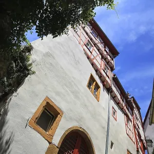Maison à colombages de grande taille avec des portes et des fenêtres rouges sous un ciel bleu à Bad Wimpfen.
