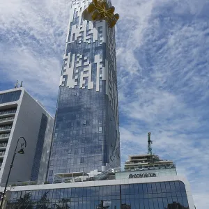 A large high-rise building with a glass facade stands in an urban environment
