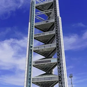 Large modern tower rising into the sky with scattered clouds in the background Large modern tower rising into the sky with scattered clouds in the background