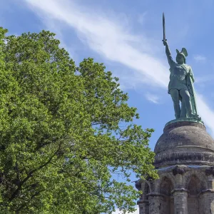 Large statue on a monument standing next to trees and under a blue sky Large statue on a monument standing next to trees and under a blue sky