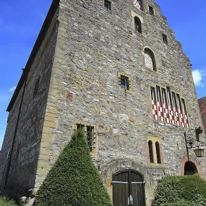 Maison en pierre de grande taille avec des fenêtres distinctives et charpenterie.