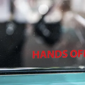 Lateral partial view of the side window of a vintage car with the inscription hands off