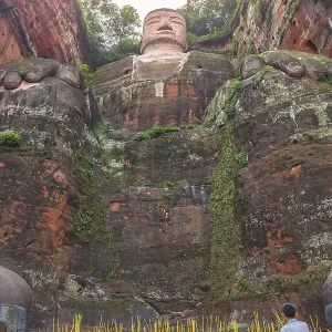Leshan, China - July 2019 : Chinese male pilgrim lightening memorial candles at the bottom of The Giant Leshan Buddha Leshan, China - July 2019 : Chinese male pilgrim lightening memorial candles at the bottom of The Giant Leshan Buddha