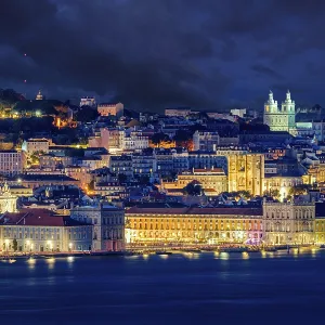 Lisbon historic old town with vibrant city lights under dramatic night sky