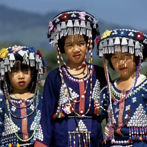 Three Lisu girls wearing colourful headdresses and the traditional costume of the mountain people