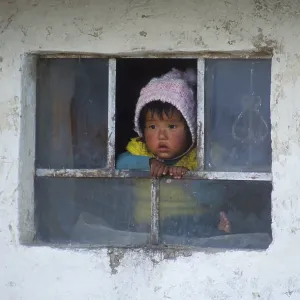 Little child looking out of a window near Cusco