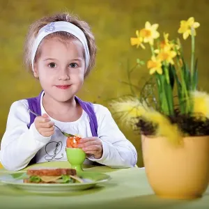 Little girl eating an Easter egg at a table