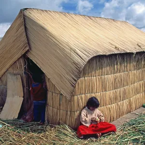 Little girl sitting in front of a reed hut on a floating Uro island in Lake Titcaca