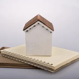 Little model house placed on an a brown color notebook Little model house placed on an a brown color notebook