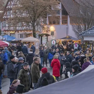 Lively Christmas market in front of half-timbered houses and trees Lively Christmas market in front of half-timbered houses and trees