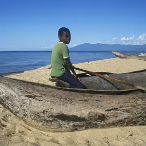 Local boy sitting on a dugout near Kande Beach on Lake Malawi Local boy sitting on a dugout near Kande Beach on Lake Malawi