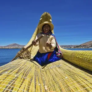 A local woman rowing a traditional boat made of totora reeds on Lake Titicaca A local woman rowing a traditional boat made of totora reeds on Lake Titicaca