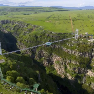 A long bridge with a glass platform spans a deep gorge