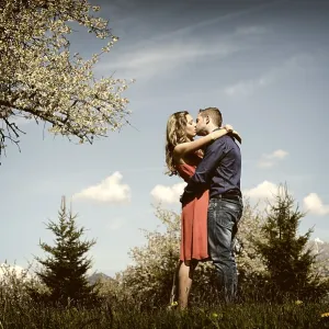 Lovers kissing next to a flowering tree in the spring