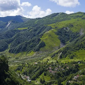 Lush green mountains with scattered village under blue sky and clouds Lush green mountains with scattered village under blue sky and clouds