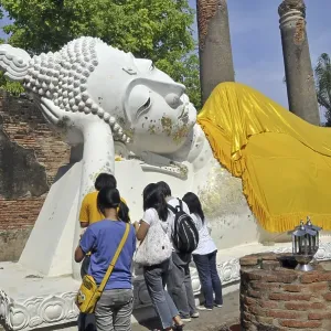 Lying Buddha statue decorated with gold leaf and ornate tunics