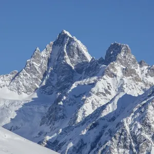 Les sommets majestueux de montagnes recouvertes de neige s'élèvent contre un ciel bleu clair.