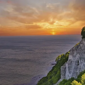Majestic view of cliffs on a coast with a glowing sunset in the background