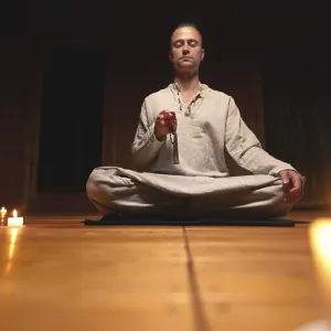 A man in clothes for practice and meditation sits in a lotus pose