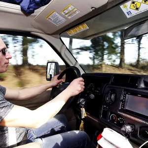 A man drives an RV on a tree-lined road