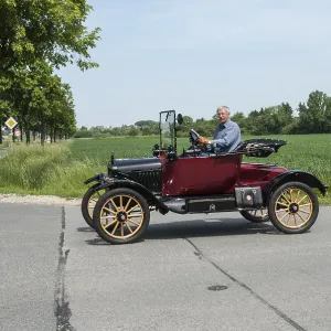 Man driving a classic Ford vintage car on an open country road Man driving a classic Ford vintage car on an open country road