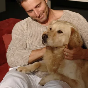Homme avec un Golden Retriever assis sur un canapé. Homme avec un Golden Retriever assis sur un canapé.