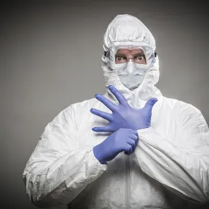 Man with intense expression wearing HAZMAT protective clothing against A gray background