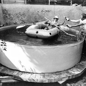 Man with lifejacket in inflatable dinghy in paddling pool