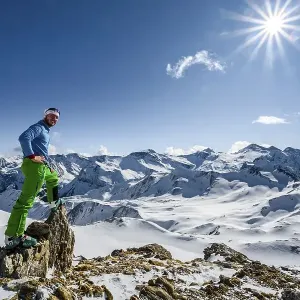 Man, ski tourer looks over snow-covered mountain ranges Man, ski tourer looks over snow-covered mountain ranges