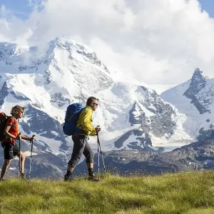 A man and a woman hiking, Schweifinen Plateau at the back the mountains Breithorn and Klein Matterhorn, Zermatt, Canton of Valais, Switzerland, Europe A man and a woman hiking, Schweifinen Plateau at the back the mountains Breithorn and Klein Matterhorn, Zermatt, Canton of Valais, Switzerland, Europe